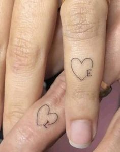 two people with tattoos on their fingers and one has the letter e in the middle