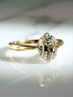 a close up of a diamond ring on a white surface