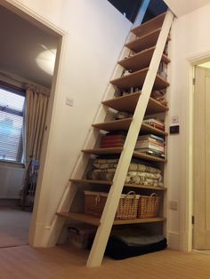 a stair case with baskets on the bottom and shelves below it in a living room