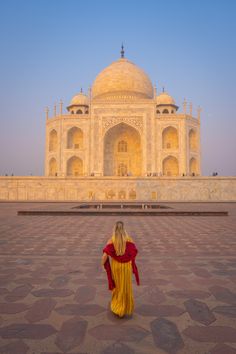 a woman standing in front of the tajwa at sunset with her back turned to the camera