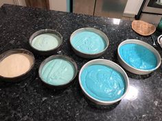 four pans filled with blue and white batter sitting on top of a kitchen counter