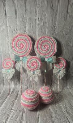 pink and white lollipops are hanging from strings on a gray background with other lollipops