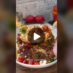 a person is holding a spoon over a bowl of food that includes meat and vegetables