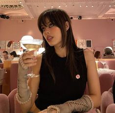 a woman sitting at a table with a glass of wine in her hand and an arm tattoo