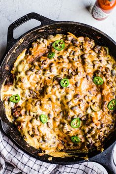 a skillet filled with cheese, black beans and green peppers next to a glass of orange juice