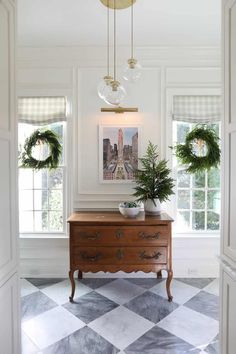 an entryway with two wreaths on the wall and a chest of drawers in it