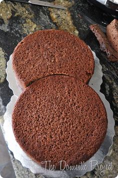 two chocolate cakes sitting on top of a counter next to a knife and some bread