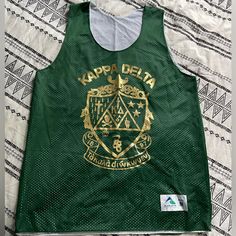 a green tank top with the words kapaa delta printed in gold on it