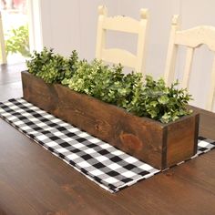 a wooden planter filled with green plants on top of a table