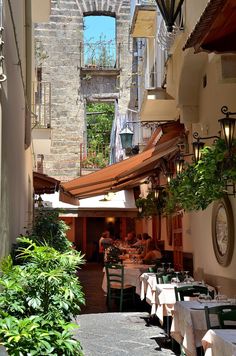 an alley way with tables and chairs lined up along the side walk, in between two buildings