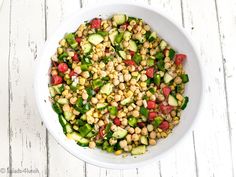 a white bowl filled with cucumber, chickpeas and other veggies