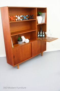 a wooden shelf with bottles and vases sitting on it's sides, against a white wall