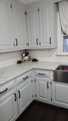 a kitchen with white cabinets and black handles on the countertop, along with a dishwasher