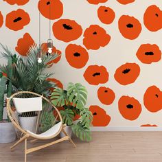 an orange flowered wallpaper is next to a chair and potted plant