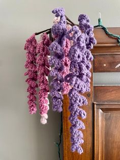 some crocheted flowers hanging from a hook on a door handle in front of a wall