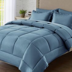 a bed with blue comforters and pillows on it