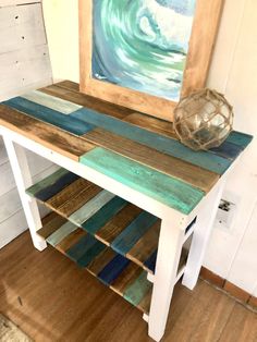 a wooden table topped with lots of different colored wood planks next to a painting