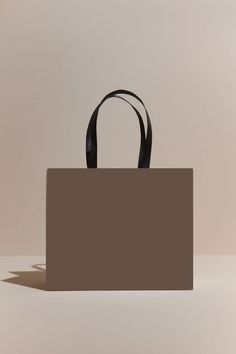 a brown shopping bag sitting on top of a white table next to a black object