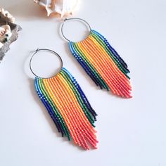 a pair of earrings with multicolored beads hanging from it's hoops