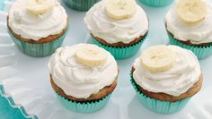 cupcakes with white frosting and banana slices on top are sitting on a paper plate