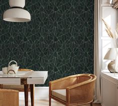 two chairs and a table in front of a wallpapered room with green geometric designs