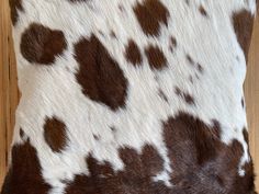 a brown and white animal print pillow sitting on top of a wooden floor