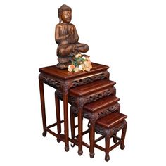 three wooden stools with a buddha figurine sitting on top of one table