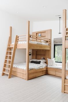 bunk beds in a room with white carpeting and wooden ladders on the wall