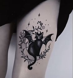 a black and white photo of a bat tattoo on the side of a woman's thigh