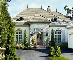 a large white house with lots of trees and bushes around it's front entrance