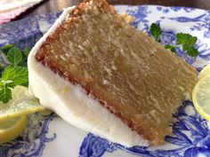 a piece of cake sitting on top of a blue and white plate next to lemon wedges