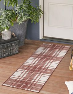 a brown and white rug sitting on top of a wooden floor next to a potted plant