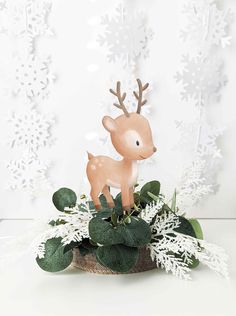 a deer figurine sitting on top of a planter filled with snowflakes