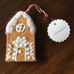 a gingerbread house ornament with a tag attached to it on a wooden table