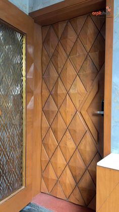 an open wooden door with decorative panels on the outside and inside, in front of a tiled wall