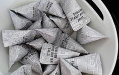 a white bowl filled with lots of candy wrappers on top of a black and white table