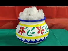 a colorful pot with cotton in it sitting on a green surface