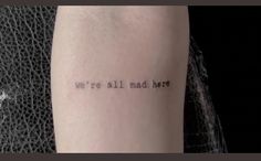 a person with a tattoo that says we're all mad here on their arm