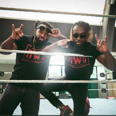 two young men standing next to each other on top of a wrestling ring with their hands in the air