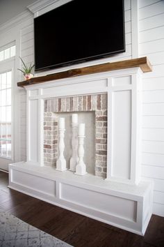 a tv mounted above a fireplace in a living room with white walls and wood floors