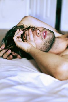 a man laying on top of a bed with his eyes closed