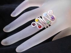 three rings with different colored stones are on a white mannequin's hand