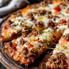 a close up of a pizza on a wooden platter with cheese and meat toppings