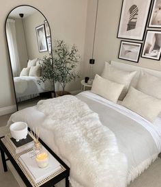 a bed with white fur on it in a room next to a mirror and coffee table