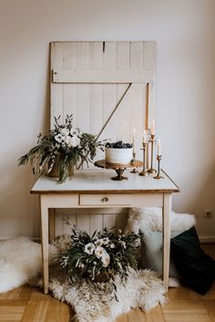 a table with flowers and candles on it in front of a wooden door that is open