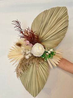 a person holding an umbrella with flowers and feathers on the inside, while another hand reaches out to touch it