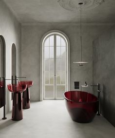 a bath room with a large red tub next to two sinks and a round window