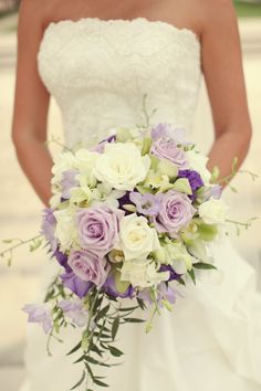 a bride holding a bouquet of purple and white flowers