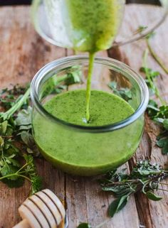 a glass filled with green liquid sitting on top of a wooden table