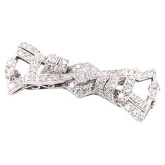 An Art Deco palladium and diamond brooch, comprising one large round brilliant cut diamond, forty-four smaller single cut diamonds, set in palladium, with palladium pin and fittings. This brooch is designed as a stylised bow. A late Art Deco take on a classic bow brooch, with striking angles and well-thought openwork – a highly coveted piece. The brooch is set to the centre with the largest diamond, a round brilliant cut, which is elegantly set within a hexagonal setting, complete with millegrain edging. Two sets of 3 diamonds are set above and below, within chevron shapes, allowing the central diamond to appear as if it were surrounded by another hexagon. Angular diamond set sections sweep out from the centre, interjected by curved lines of diamonds, creating the stylised ‘ears’ of the bo Layered Diamond Necklace, Late Art, Bow Brooch, Diamond Brooch, Curved Lines, Diamond Set, Round Brilliant Cut Diamond, Brilliant Cut Diamond, Makers Mark